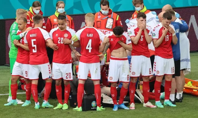 Denmark players form a human shield around Eriksen while holding up the Finnish flag thrown by the Finland fans