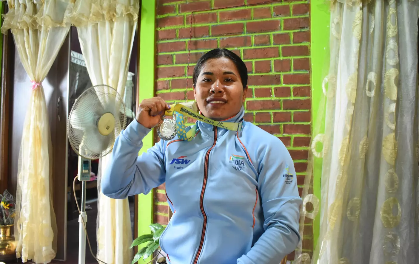 Bindyarani Devi holds aloft her CWG medal in the living room of her house