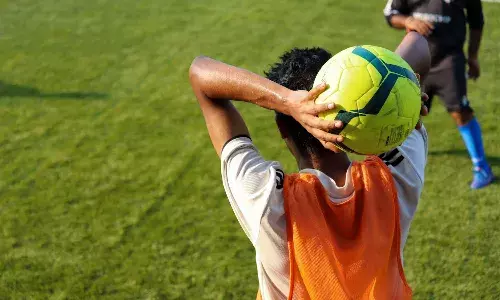 Man in orange jersey holding yellow soccer ball
